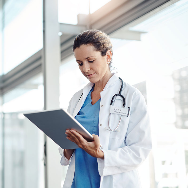 Female dr. wearing medical coat holding electronic clipboard