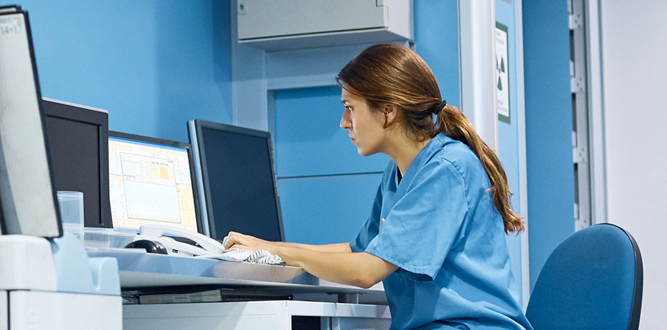 A female health information technology specialist is at work on a computer