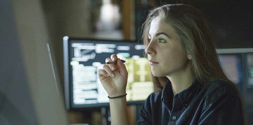 A female IT cyber and networki security professional is looking at a computer