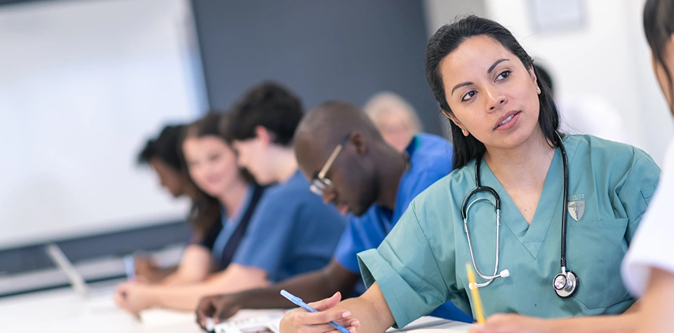 A female medical assistant student is sitting in a classroom with other students