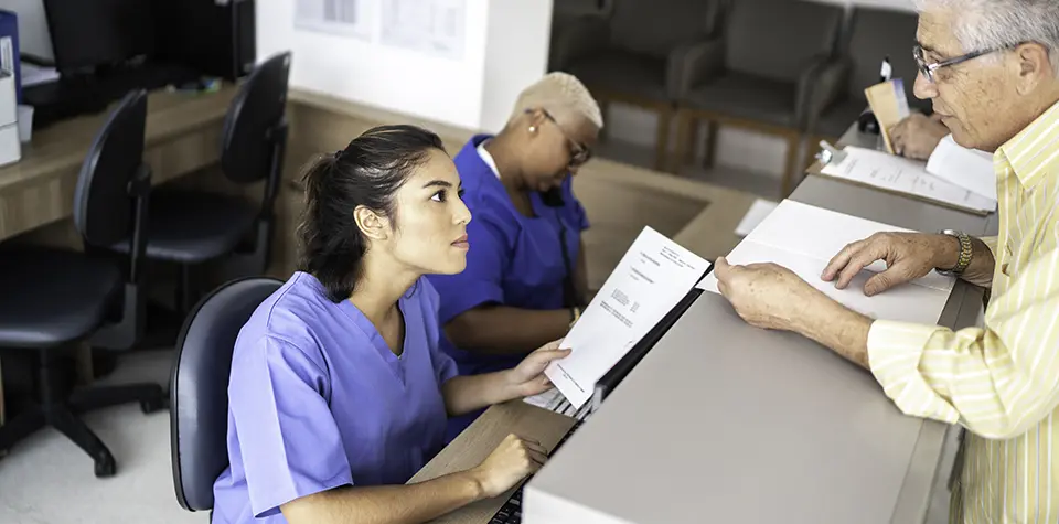 a female medical assistant is helpinf a patient