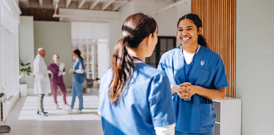 Two young female nurses are talking to each other in a medical building